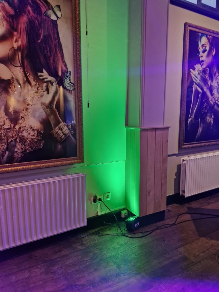 City of Taste | Eetwinkel Vier Groene verlichting naast een muur met grote kunstwerken.